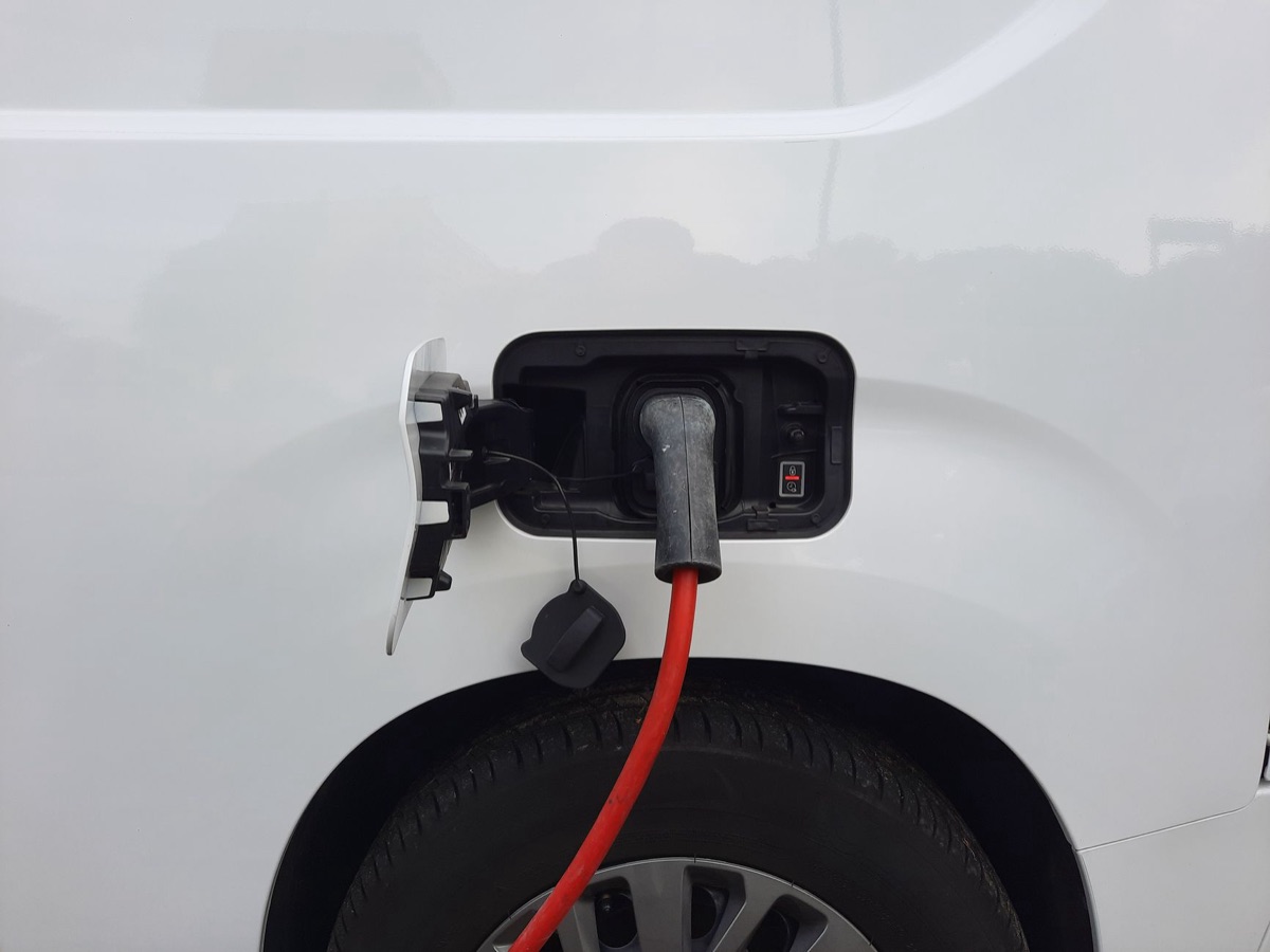 A close-up shot of an EV charging plug connected to a car.