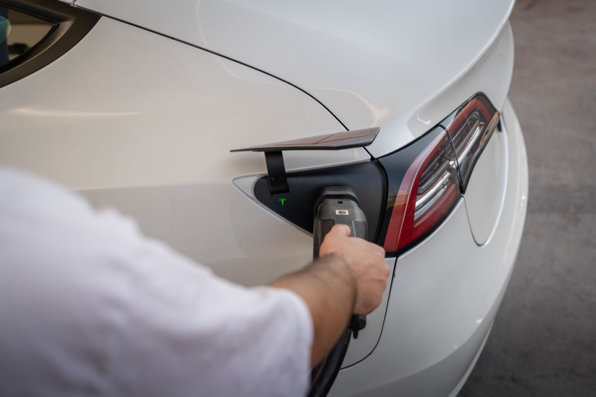 Een witte Tesla Model 3 geparkeerd in een moderne stedelijke omgeving