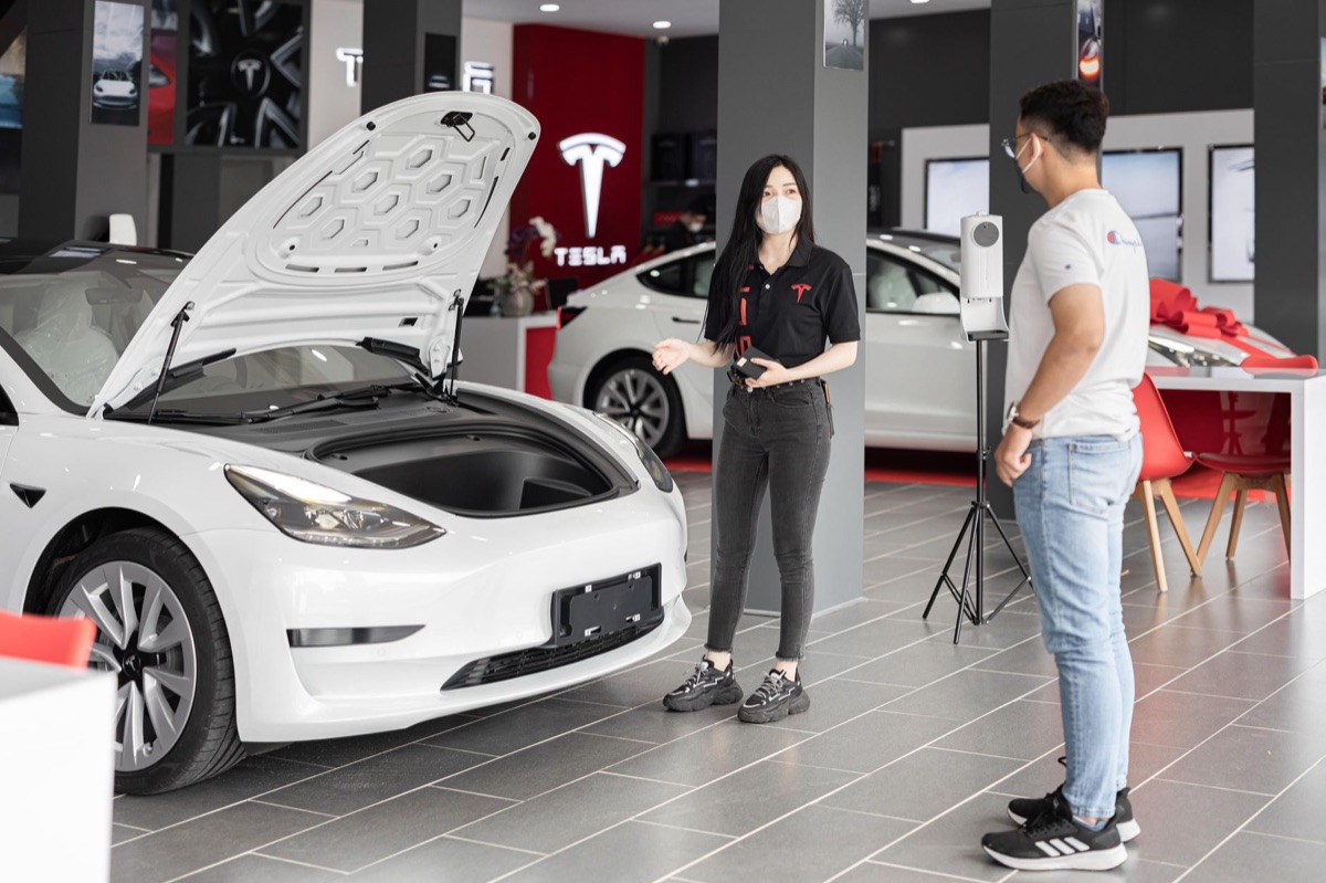 Um Tesla Model 3 moderno estacionado em uma rua urbana.